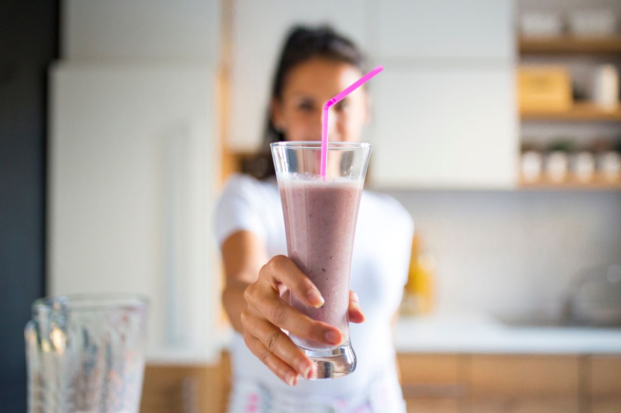 Woman holding a berry blast skin loving smoothie